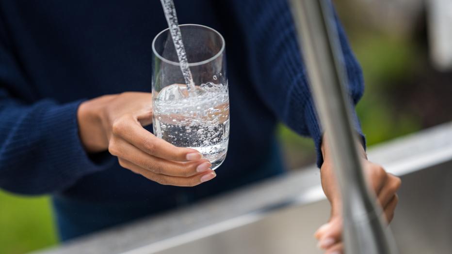 Woman's hands filling glass with water stock photo