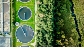 Stock image depicting water treatment facility, surrounded by bright greenery