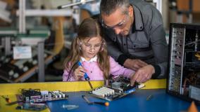 Man works with young girl on a electronics project