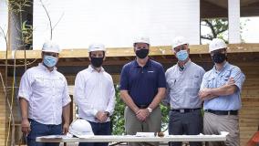 Five men in hard hats and masks standing on a construction site