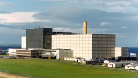 Large building facility with blue sky background and green grass forefront