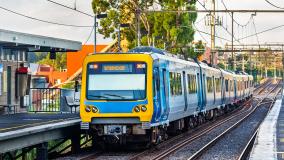 Yellow and blue train on tracks rolling into a station