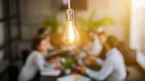 lightbulb in front of out of focus group of people at table