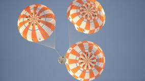 Orange and white parachutes in sky