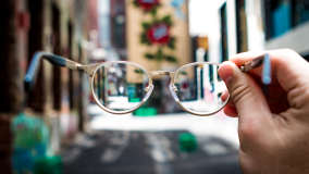 Streetscape out of focus with glasses in foreground helping focus