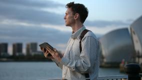 man holding computer tablet standing by Thames Barrier