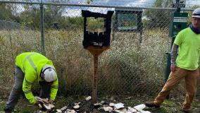 Two teammates in PPE with the charred little library