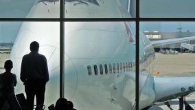 Two people looking at Delta airplane through terminal window