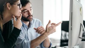 Woman and man looking at a desktop Mac 