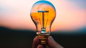 Lightbulb being held by person with sunset in background