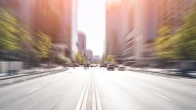 Blurred image of a road facing toward a downtown with office buildings