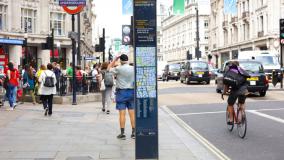 Entrance to Oxford Street London Underground station. Street with people walking, cyclists, taxis and other traffic