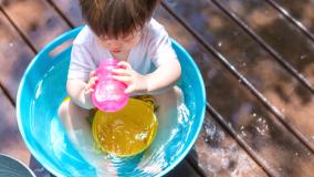 Toddler in a kiddie pool drinking out of a pink sippy cup