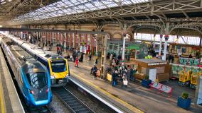 Two trains at platforms in Preston Station in the north west of England in the UK. The architecture of the roof is visible.