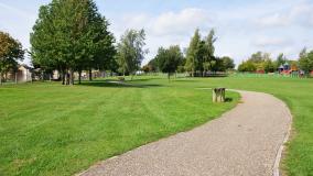 Green park with path, trees, green grass and playground.