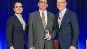 Raj Badhwar collecting an award from two other people