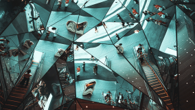 Abstract mirrored ceiling reflecting escalators, stairs, and people in a kaleidoscopic pattern