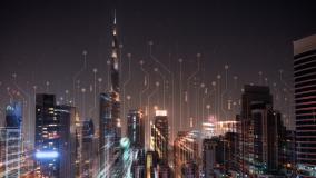 A nighttime cityscape featuring tall, illuminated buildings, overlaid with abstract digital circuit patterns to symbolizing technology and connectedness