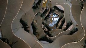 Spiral mirrored structure reflecting greenery and decorative elements inside