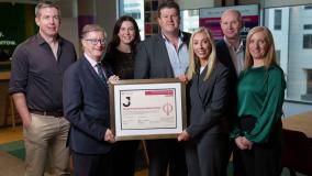 Group of six people in an office setting receiving a framed certificate of the CPD recognition.