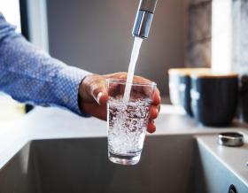 man filling glass of water from faucet