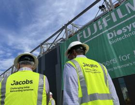 Koti Vadlamudi and Bob Pragada in yellow PPE vest and white hard hats look on to the Fujifilm Diosynth Biotechnologies facility unveiling