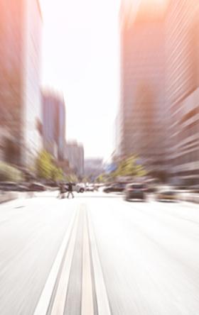 Blurred image of a road facing toward a downtown with office buildings