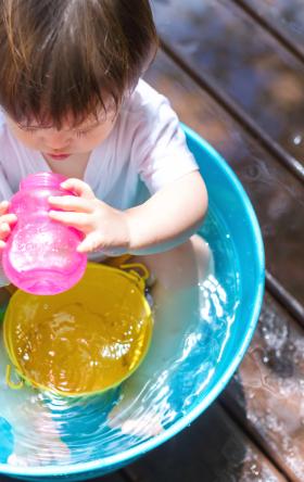 Toddler in a kiddie pool drinking out of a pink sippy cup