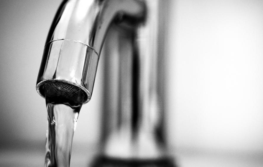 Stock image of a silver faucet with water flowing out