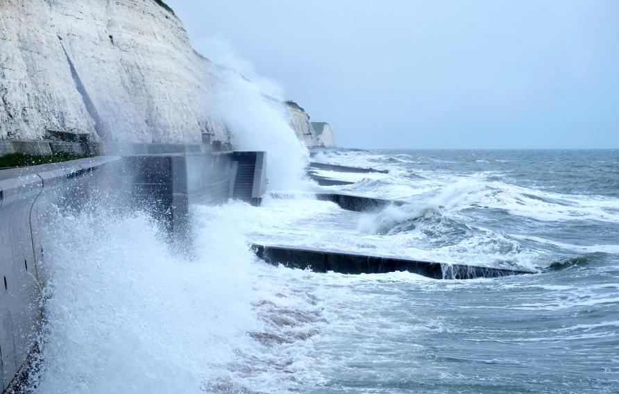 Sea spray and waves hitting coastal walkway