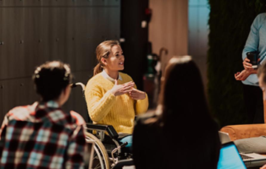 Woman in wheelchair presenting to a team