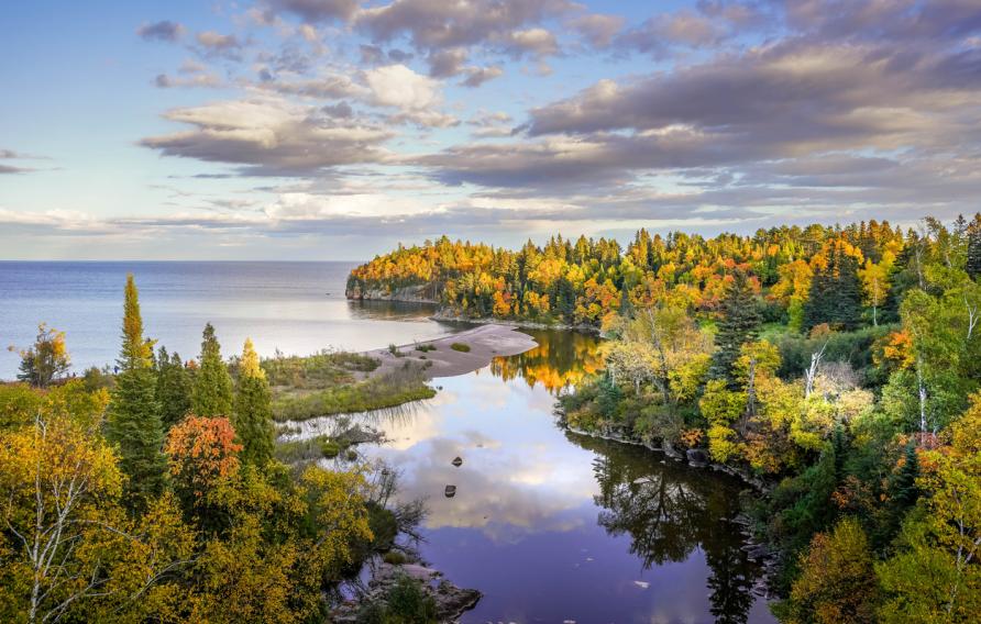 Beautiful reflections of clouds and Autumn colors on the Baptism River where it meets Lake Superior at Tettegouche State Park, Minnesota