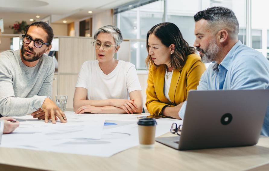 Group of five individuals brainstorming round a table