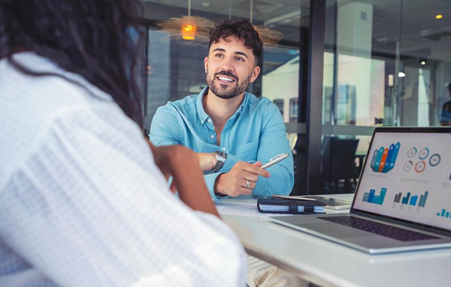 Two people talking and looking at analytics on a laptop