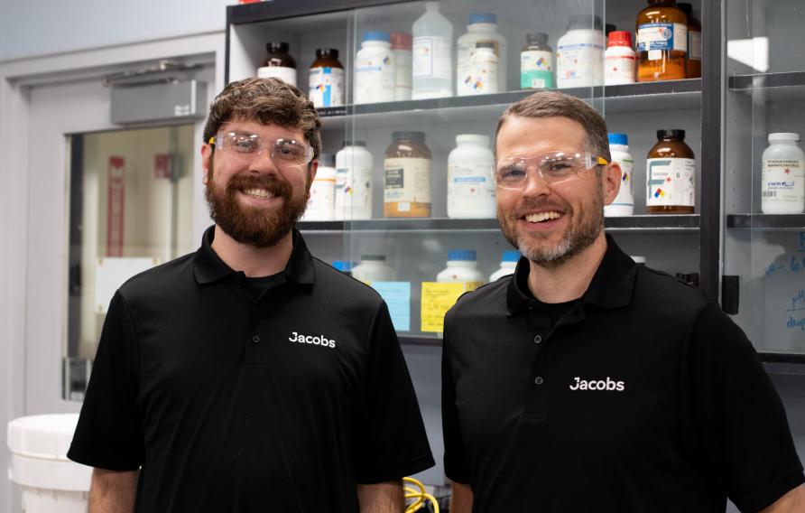 Jacobs operators in a labroom in clear safety goggles and black Jacobs-branded polos