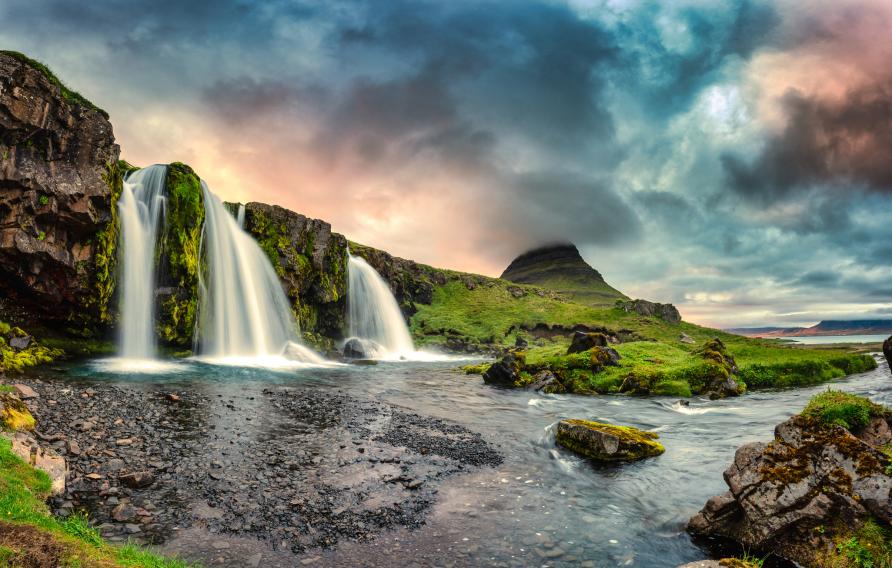 Fantastic landscape of sunset over Kirkjufell mountain with Kirkjufellsfoss waterfall and colorful pileus cloud on summer at Iceland