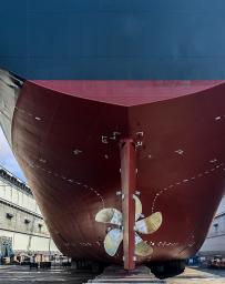 Underside of large ship with a fan at a dock