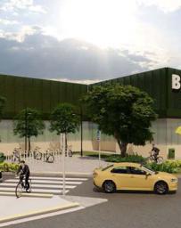 Rendering of a train station building with a crosswalk, biker and yellow mid-size sedan in the foreground