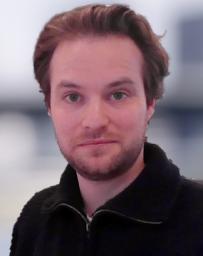 Man with light brown hair dressed on dark half zip fleece.
