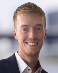 Headshot of man with blonde hair, wearing a white shirt and dark blue jacket. 