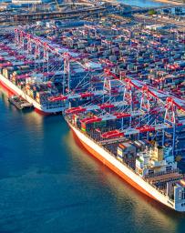 Aerial view of two large cargo ships moored in port at Long Beach, California being loaded with containers shot via helicopter from an altitude of about 800 feet.