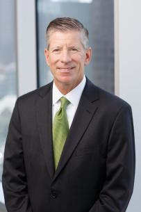 White man with silver hair in a black suit jacket white dress shirt and lime green tie