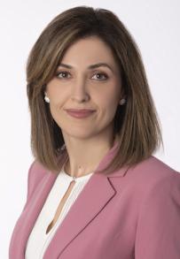 Medium skinned woman with brown short hair in a pink suit coat and white blouse