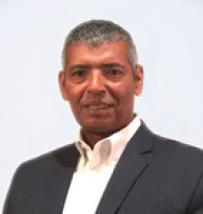 Black man with grey hair in black suit coat and white dress shirt no tie