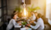 lightbulb in front of out of focus group of people at table