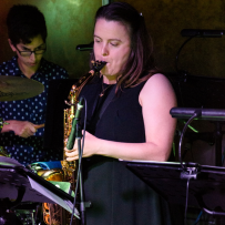 Dark haired woman plays saxophone