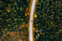 Red car traveling through colorful fall foliage