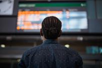 man in control room looking up at large screen depicting various data