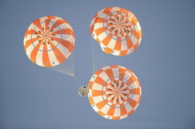 Orange and white parachutes in sky