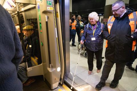 Image showing train guard guiding female passenger onto train, with step free access